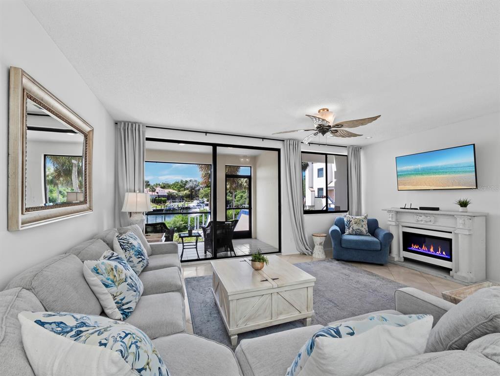 A living room features a grey sectional sofa, fireplace, and sliding doors opening to a balcony — 1906 HARBOURSIDE DRIVE UNIT 303, LONGBOAT KEY, FL