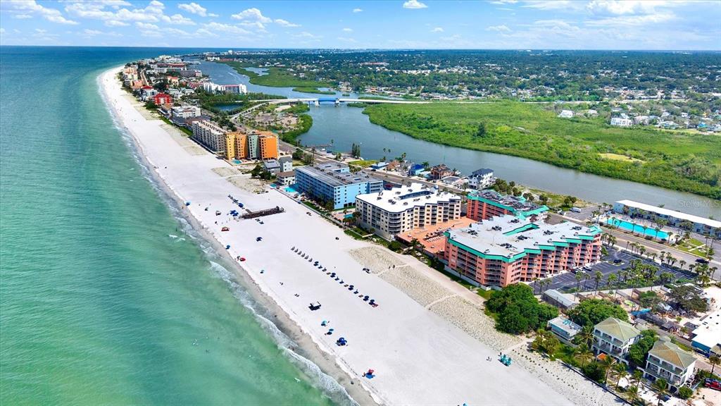 An aerial view shows a sandy beach, turquoise ocean, and several multi-story residential buildings — 18450 GULF BOULEVARD UNIT 213, INDIAN SHORES, FL