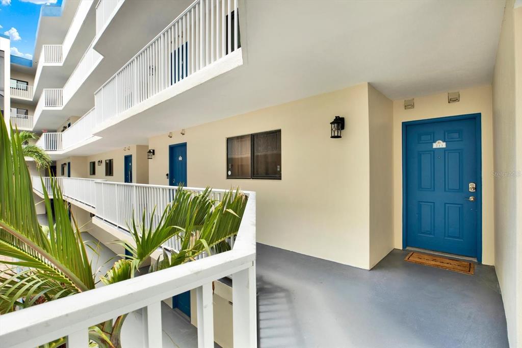 An exterior view of a multi-story apartment building with blue doors and white railings — 18450 GULF BOULEVARD UNIT 213, INDIAN SHORES, FL