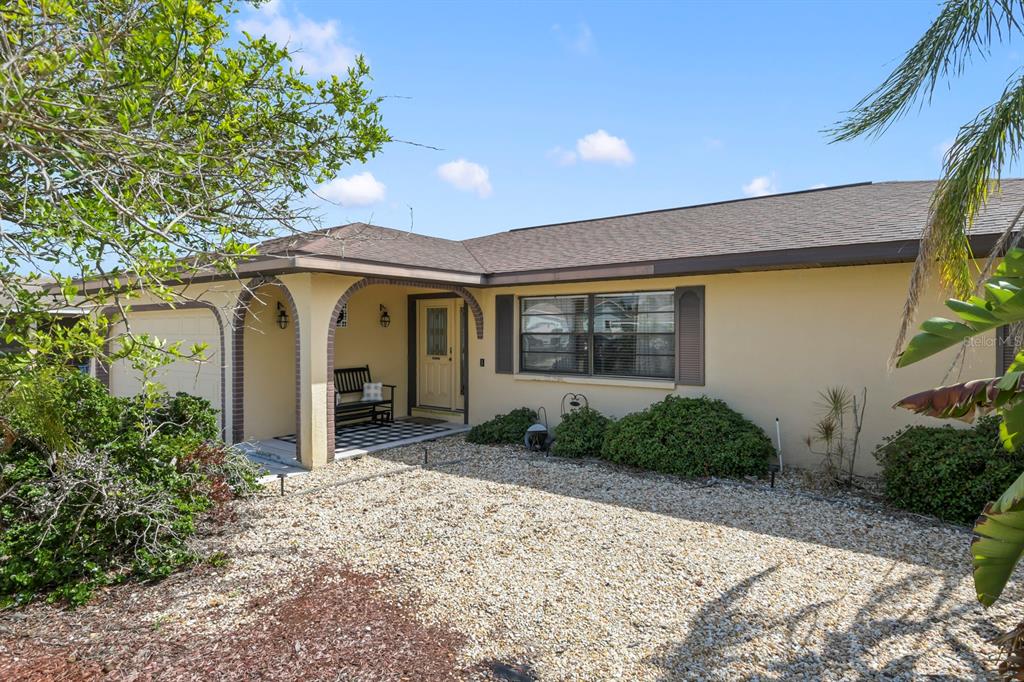 A single-story house with a beige stucco exterior, a gravel front yard, and a covered porch — 744 FLAMINGO DRIVE, APOLLO BEACH, FL