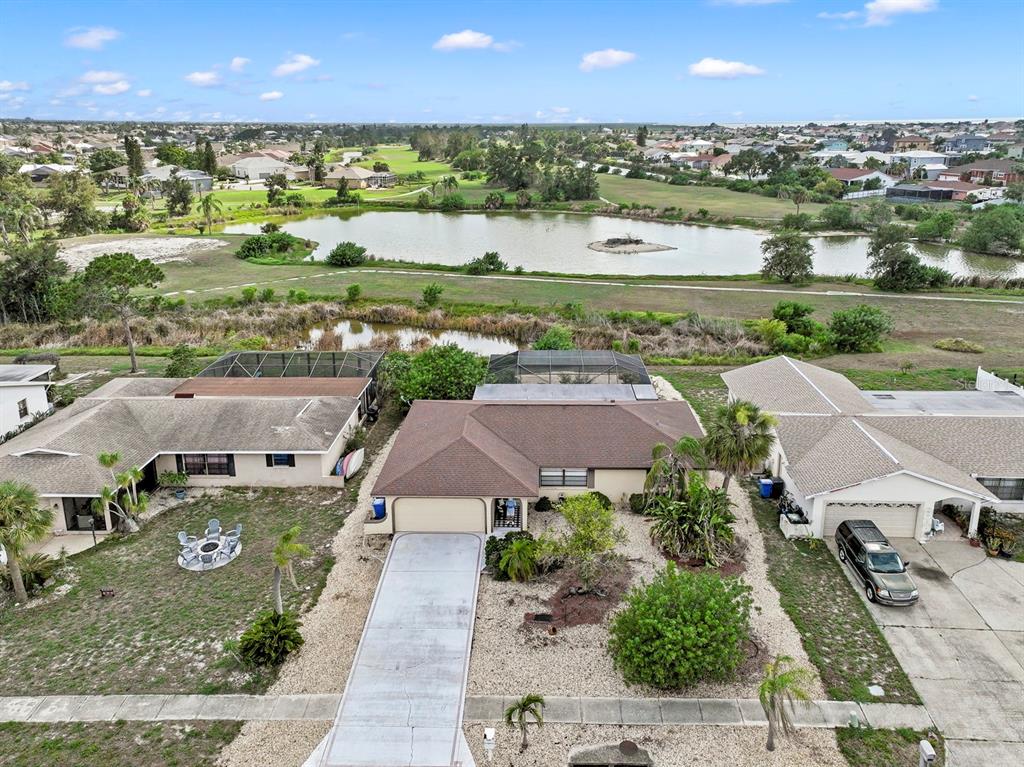 An aerial view shows a suburban house with a driveway, pool cage, and backyard pond — 744 FLAMINGO DRIVE, APOLLO BEACH, FL