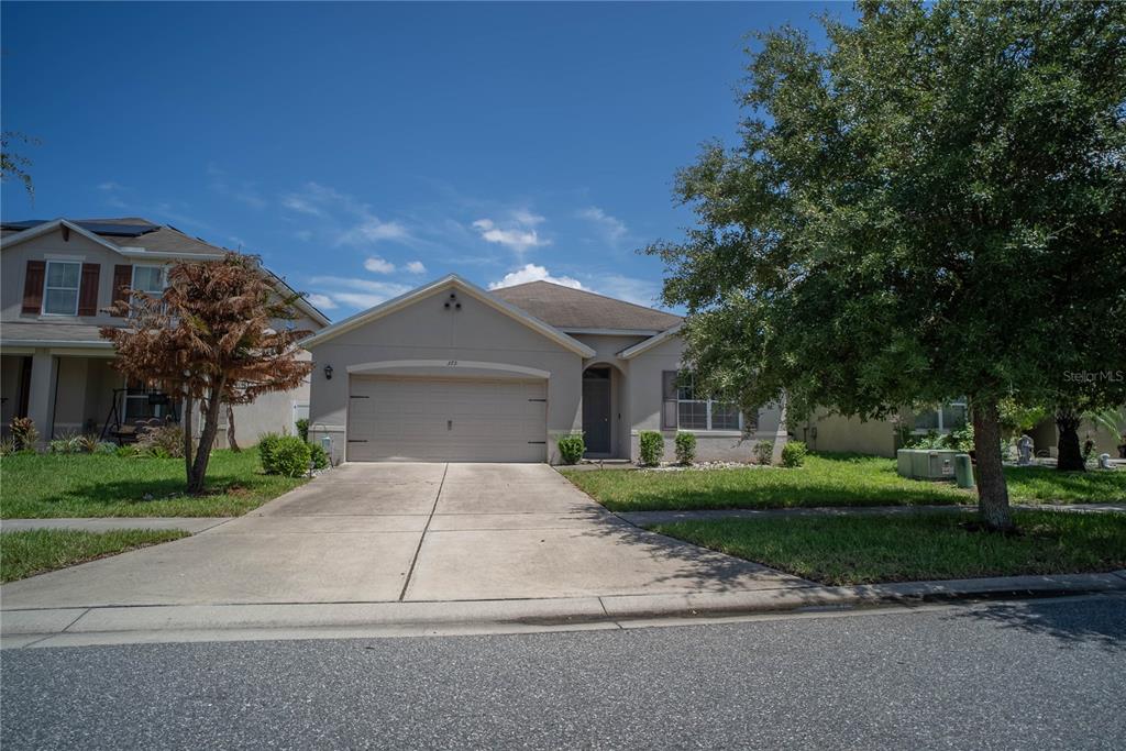 A single-story suburban house with a concrete driveway, a two-car garage, and a large tree — 373 ABERDEEN DRIVE, DAVENPORT, FL