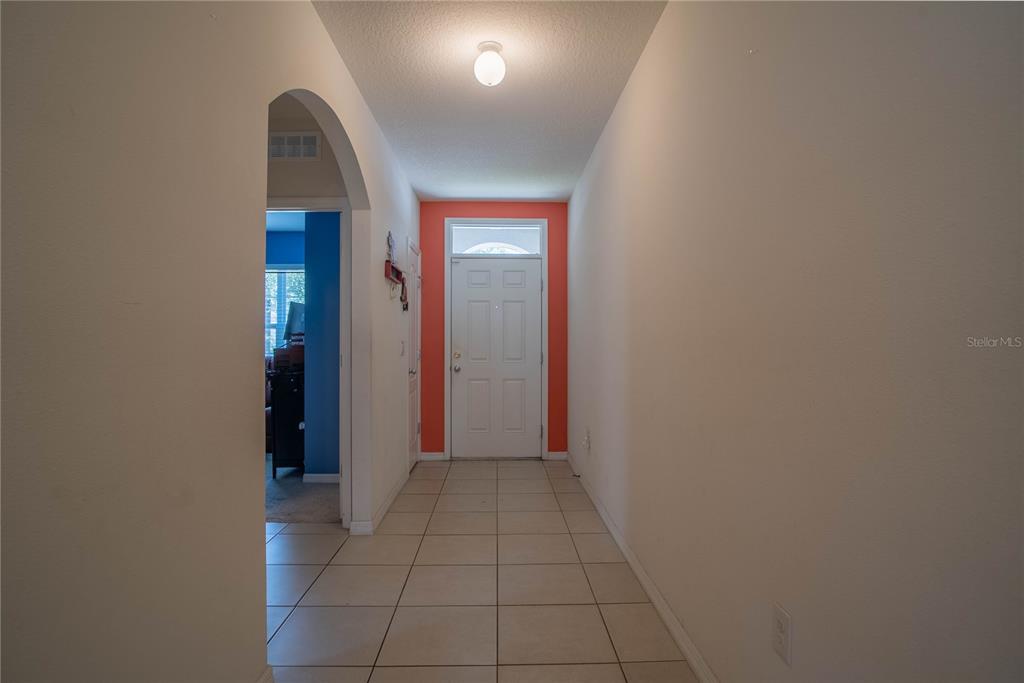 A tiled entryway features a white front door framed by a bright orange accent wall — 373 ABERDEEN DRIVE, DAVENPORT, FL