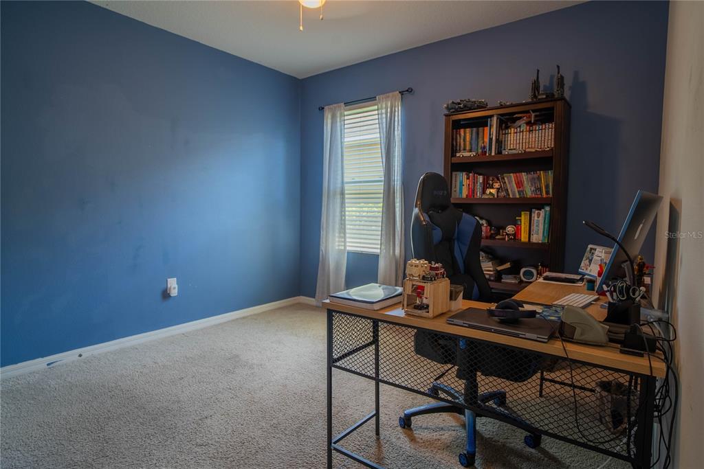 A home office with blue walls, carpeted flooring, a desk, and a bookshelf — 373 ABERDEEN DRIVE, DAVENPORT, FL