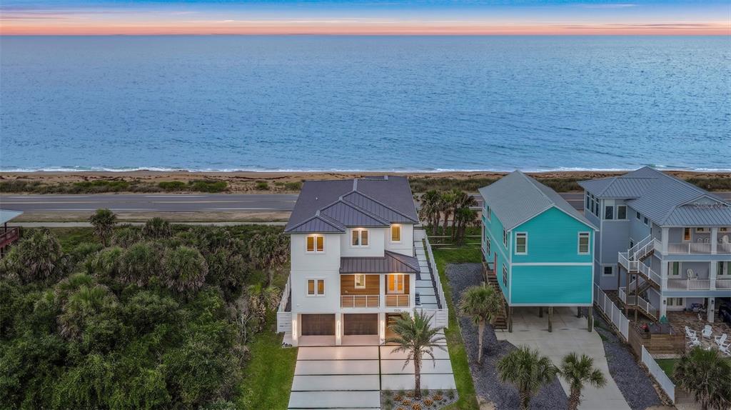 A three-story modern house with a two-car garage and a covered balcony at dusk — 2214 N CENTRAL AVENUE, FLAGLER BEACH, FL