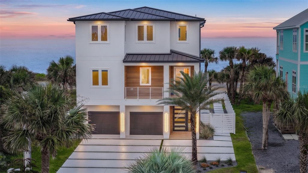 A modern kitchen with light wood cabinets and a marble island overlooks a sunset ocean view — 2214 N CENTRAL AVENUE, FLAGLER BEACH, FL