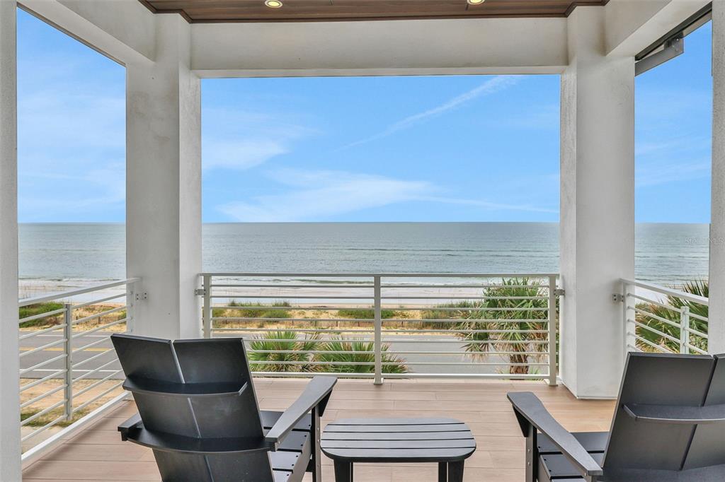 A modern kitchen features a large marble-topped island, white cabinetry, wood accents, and pendant lighting — 2214 N CENTRAL AVENUE, FLAGLER BEACH, FL