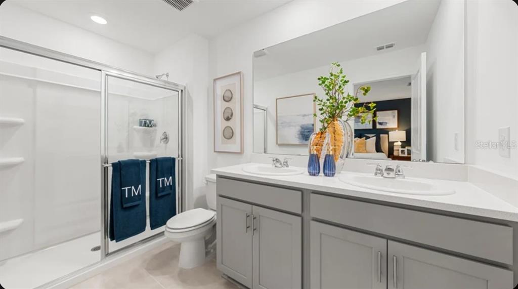 A kitchen with gray cabinets and a white island features bar stools and an adjacent living area — 7187 GRAND FOREST WAY, NOKOMIS, FL