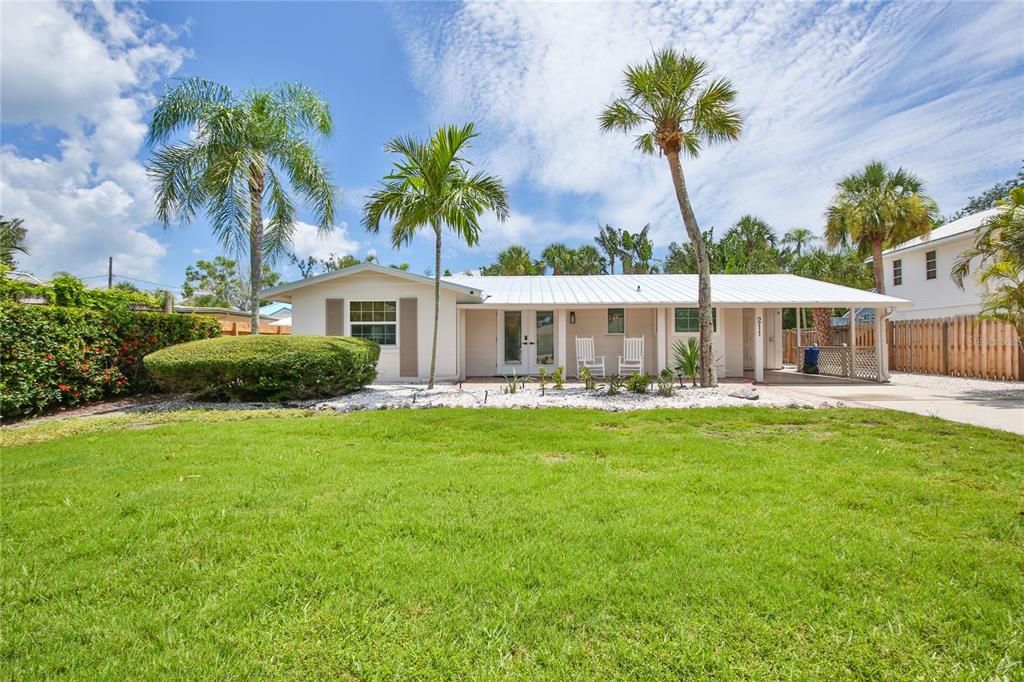 A single-story house with a white metal roof, palm trees, and a front lawn — 211 ISLAND CIRCLE, SARASOTA, FL