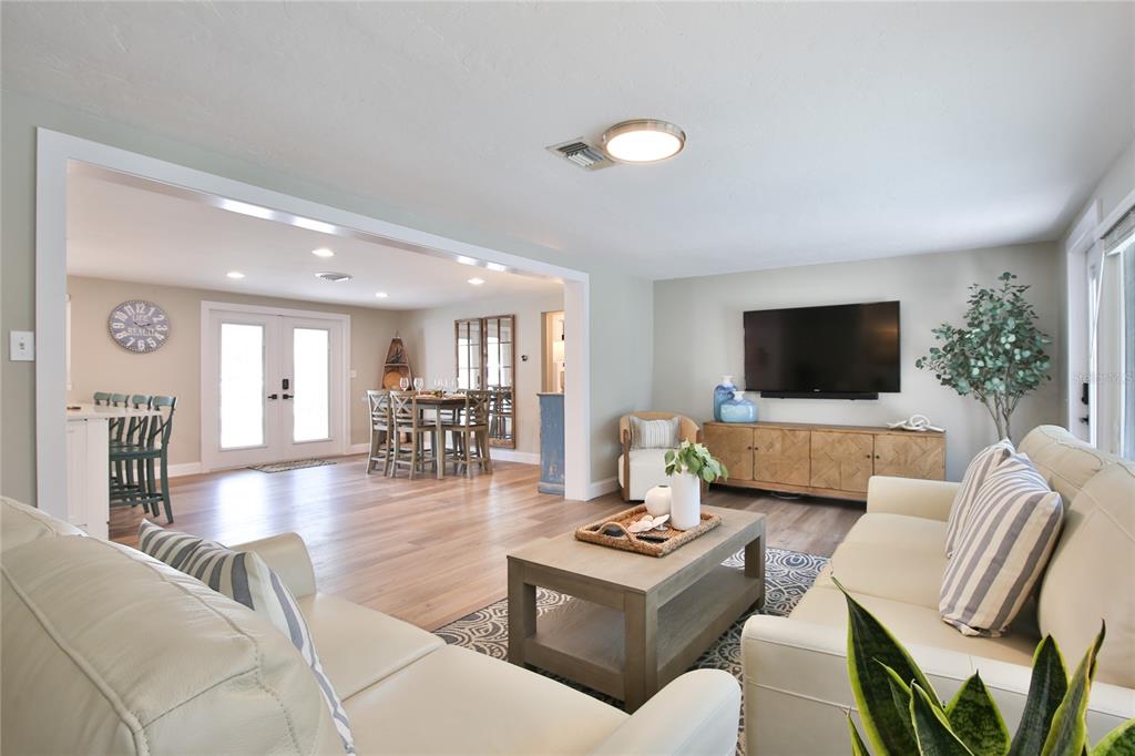 A living room with light wood floors, a beige sofa, and an open dining area — 211 ISLAND CIRCLE, SARASOTA, FL