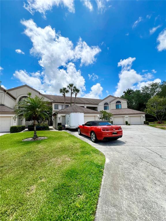 A red car is parked in the driveway of a multi-unit residential building — 3014 RED OAK COURT UNIT 102, PALM HARBOR, FL