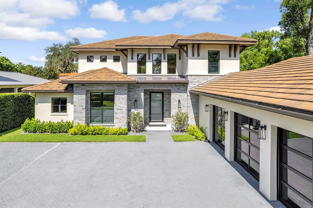 A two-story house with a stone facade, tile roof, and a paved driveway with garages — 901 GOLFVIEW TERRACE, WINTER PARK, FL