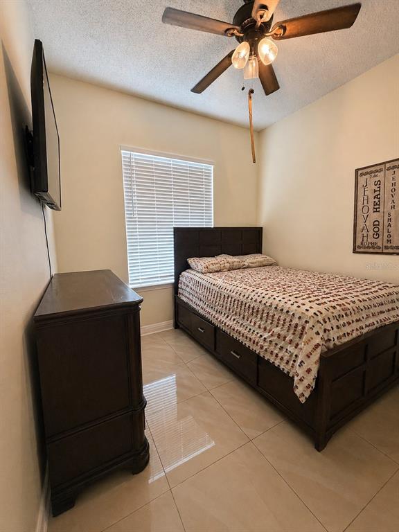 A bedroom features a dark wood bed frame with storage drawers, a dresser, and tile flooring — 3843 WEETAMOO CIRCLE, ORLANDO, FL