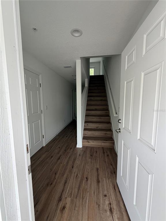 An entryway with wood-look flooring leads to a staircase and a closed white door — 2577 6TH AVENUE DRIVE E, BRADENTON, FL
