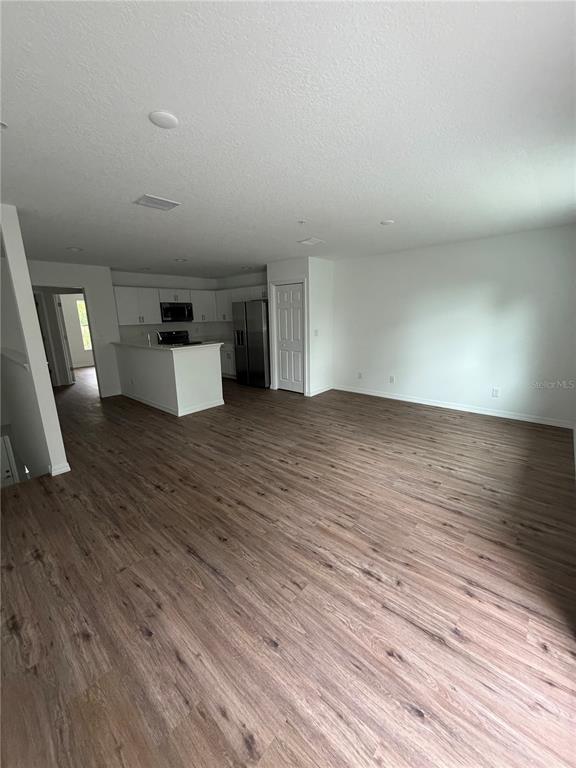 An open-concept living area features wood-look flooring and a kitchen with white cabinetry — 2577 6TH AVENUE DRIVE E, BRADENTON, FL