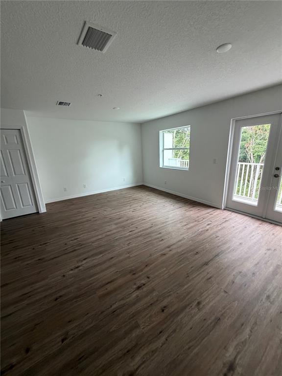 An empty room features wood-look flooring, white walls, a window, and a glass-paned door — 2577 6TH AVENUE DRIVE E, BRADENTON, FL
