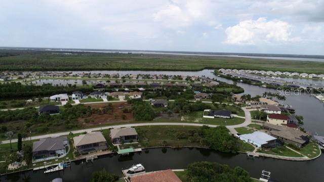 An aerial view shows waterfront houses along canals with a large undeveloped lot in the center — 15157 LEIPZIG CIRCLE, PORT CHARLOTTE, FL