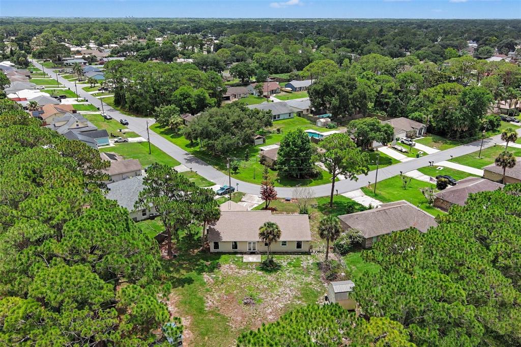An aerial view shows a single-story house with a large backyard surrounded by pine trees — 7260 FREEPORT ROAD, COCOA, FL