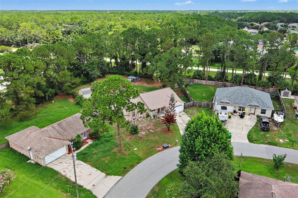 An aerial view shows three suburban houses with driveways, lawns, and surrounding trees — 7260 FREEPORT ROAD, COCOA, FL