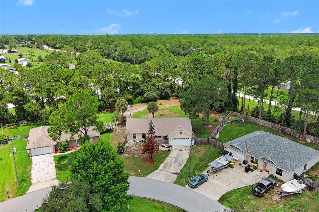 An aerial view shows three suburban houses with driveways surrounded by trees and grassy lawns — 7260 FREEPORT ROAD, COCOA, FL