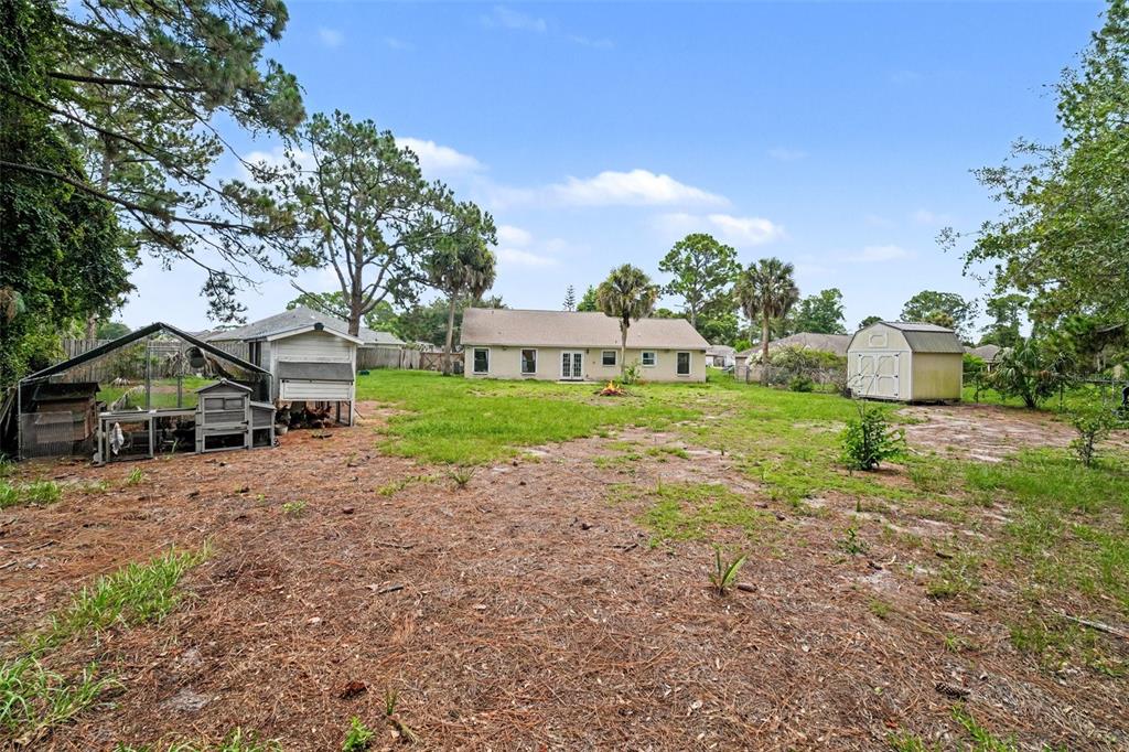 A backyard features a house, a chicken coop, and a storage shed on a grassy lot — 7260 FREEPORT ROAD, COCOA, FL
