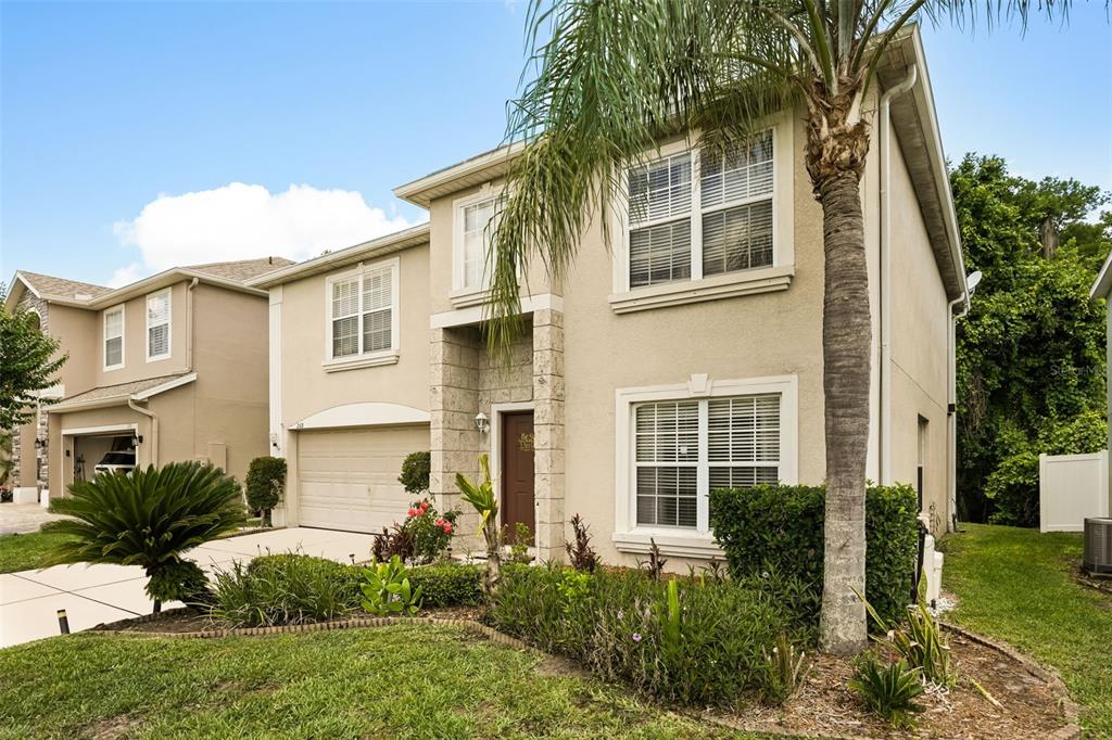 A two-story suburban house with a beige stucco exterior, a palm tree, and a driveway — 268 TAVESTOCK LOOP, WINTER SPRINGS, FL