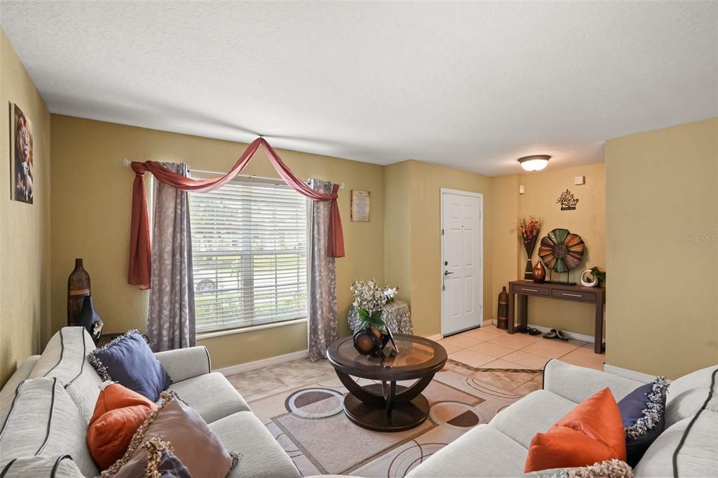 A living room features light-colored sofas, a round coffee table, and a front entryway — 268 TAVESTOCK LOOP, WINTER SPRINGS, FL