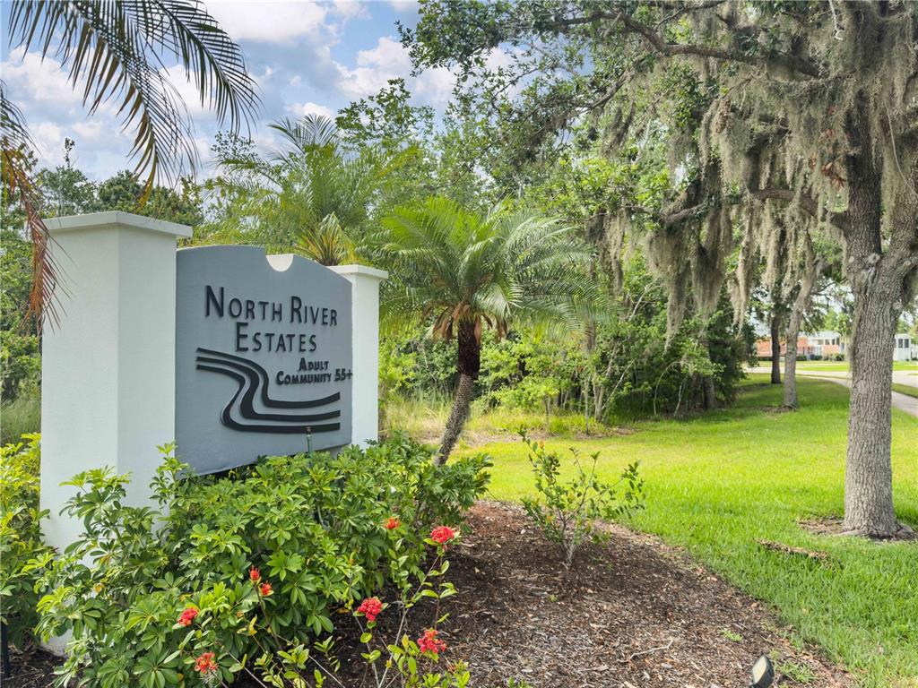 A sign for North River Estates adult community stands in a landscaped garden area — 3421 70TH AVENUE E, ELLENTON, FL