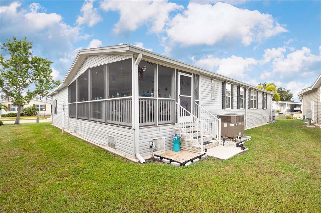 A light-colored mobile home features a large screened-in porch and a side entrance with stairs — 3421 70TH AVENUE E, ELLENTON, FL