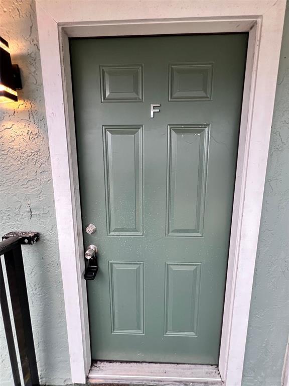 A green exterior door marked with the letter F is set within a white frame — 4170 BARNA AVENUE UNIT F, TITUSVILLE, FL