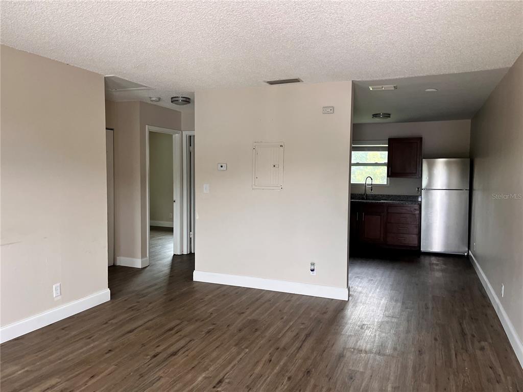 An open living area with wood-look flooring leads to a kitchen with stainless steel appliances — 4170 BARNA AVENUE UNIT F, TITUSVILLE, FL