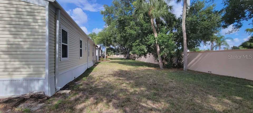 A side view of a light-colored mobile home exterior next to a grassy yard — 5208 5TH B STREET E, BRADENTON, FL