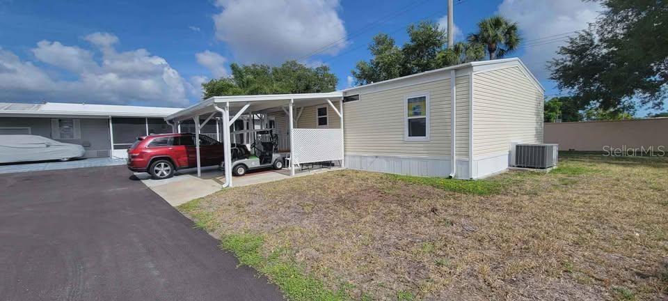 A light-colored mobile home features a carport, a red SUV, and a golf cart — 5208 5TH B STREET E, BRADENTON, FL