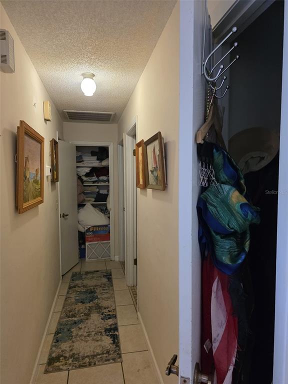 A hallway with tile floors, framed artwork, and a closet at the end — 5045 MISTY LAKE DRIVE, MULBERRY, FL