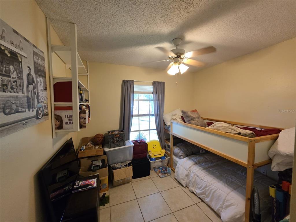 A bedroom features a bunk bed, a white shelving unit, a television, and tile flooring — 5045 MISTY LAKE DRIVE, MULBERRY, FL