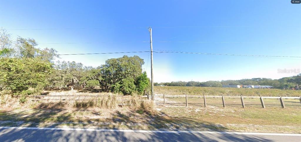 A wooden fence separates a grassy field from a wooded area under a clear sky — GERBER DAIRY RD, WINTER HAVEN, FL