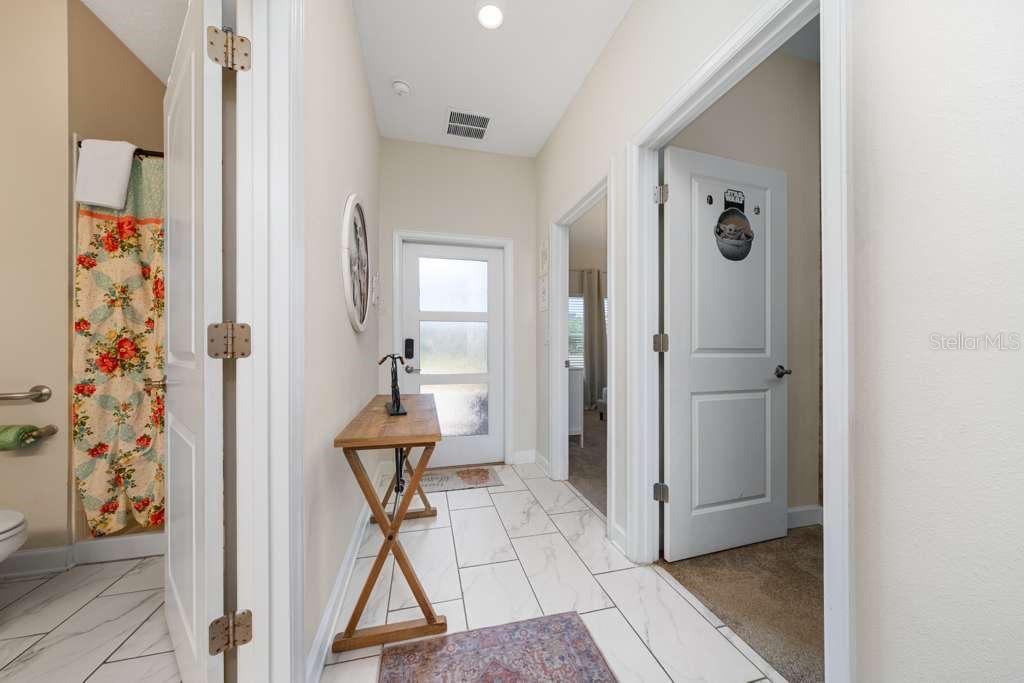 A hallway with white tile floors leads to an exterior door and two interior rooms — 8999 CABOT CLIFFS DRIVE, DAVENPORT, FL
