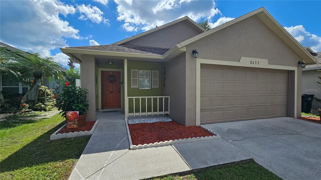 A single-story house with a beige stucco exterior, a two-car garage, and a front porch — 8632 FOLEY DRIVE, ORLANDO, FL