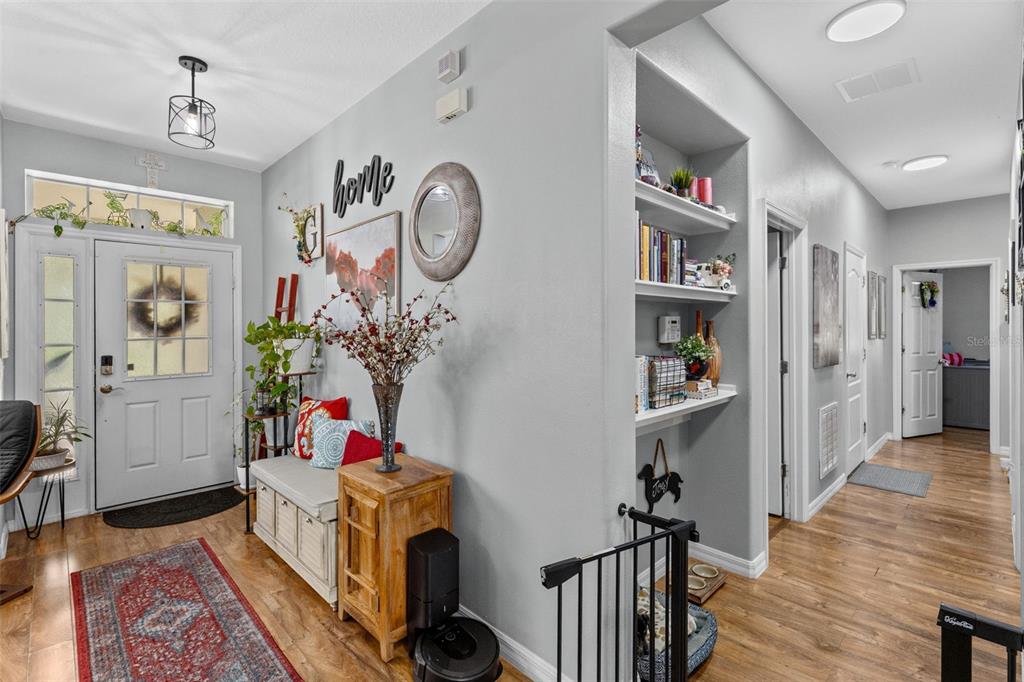 A bright entryway features a white front door, wood flooring, built-in shelving, and a bench — 8126 CRUSHED PEPPER AVENUE, ORLANDO, FL