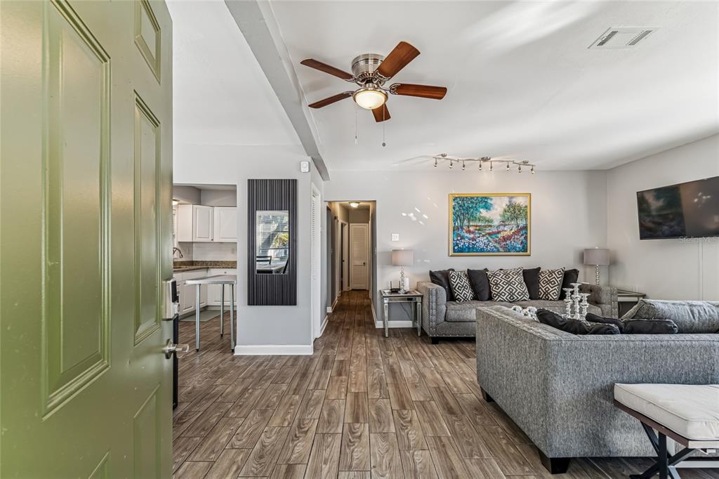 A single-story house with a green door, a screened porch, and a paved driveway at dusk — 902 BELTREES STREET, DUNEDIN, FL