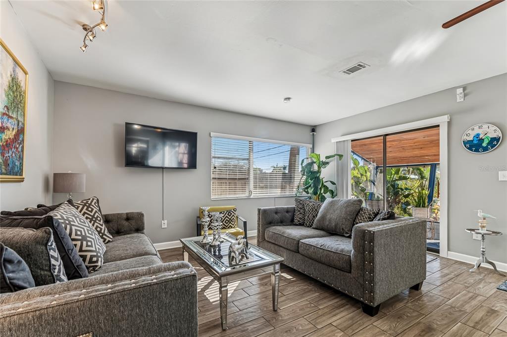A screened-in porch features a wood-plank ceiling, dark carpet, and outdoor furniture — 902 BELTREES STREET, DUNEDIN, FL