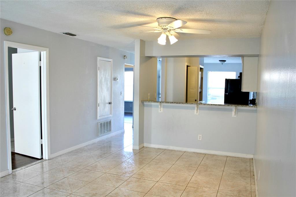 A room with light-colored tile flooring, a ceiling fan, and a kitchen pass-through window — 2321 TRINIDAD COURT, KISSIMMEE, FL