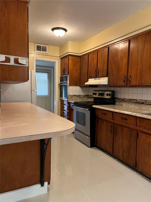 A kitchen features wood cabinets, a stainless steel oven, and a light-colored countertop — 5847 HARRINGTON DRIVE, ORLANDO, FL