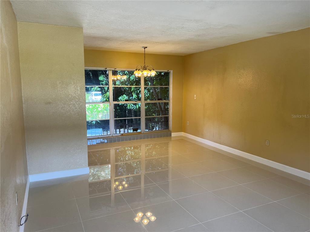 A dining room with large windows, a chandelier, and light-colored tile flooring — 5847 HARRINGTON DRIVE, ORLANDO, FL