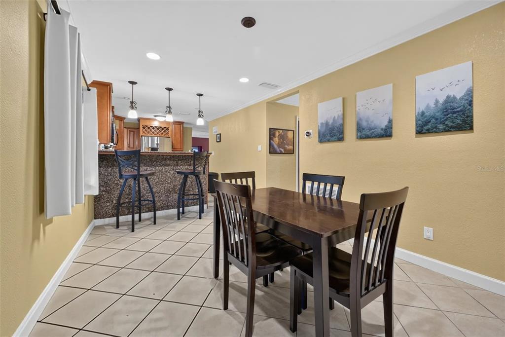 A dining area with a dark wood table and chairs adjacent to a kitchen breakfast bar — 2511 KILGORE STREET, ORLANDO, FL