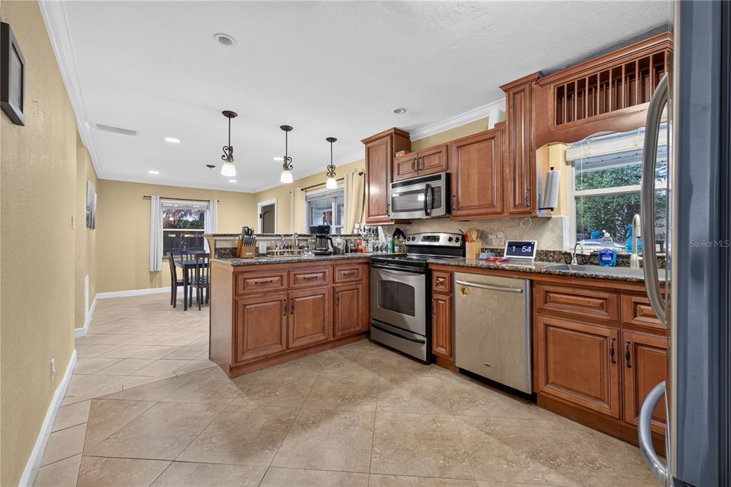 A kitchen with wood cabinets, granite countertops, stainless steel appliances, and tile flooring — 2511 KILGORE STREET, ORLANDO, FL