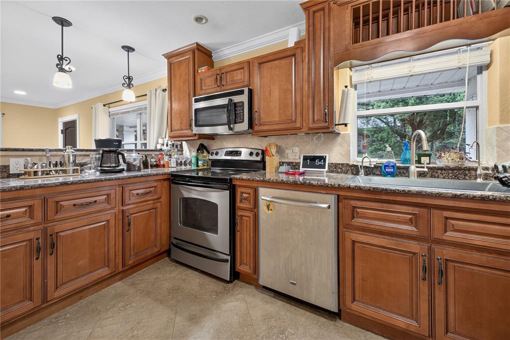 A kitchen features wood cabinets, granite countertops, stainless steel appliances, and a window above the sink — 2511 KILGORE STREET, ORLANDO, FL