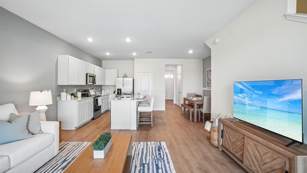 An open-concept living area features a white kitchen, dining space, and a television console — 12611 CITRUS PARK LANE, TAMPA, FL