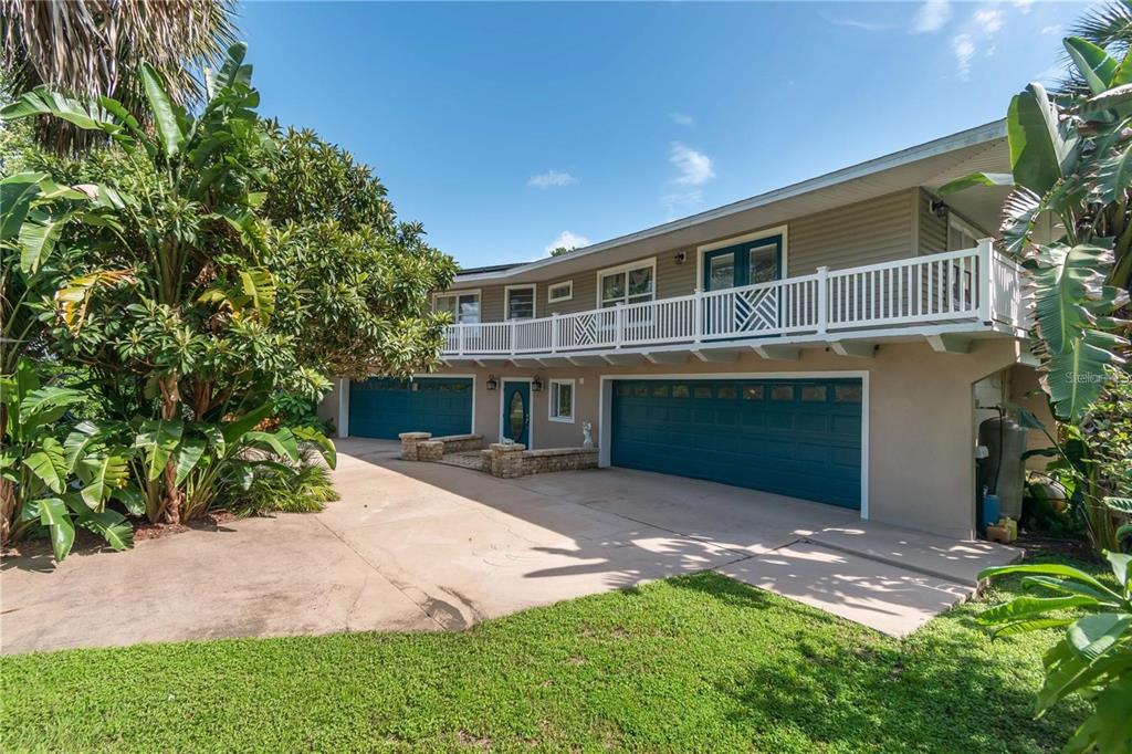 A two-story house with a white balcony, teal garage doors, and a concrete driveway — 3 SE OCALE WAY, SUMMERFIELD, FL