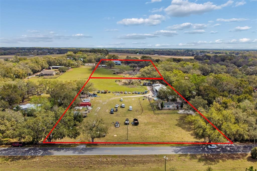 An aerial view shows a large, fenced residential lot with multiple structures and scattered vehicles — 8302 WIRE ROAD, ZEPHYRHILLS, FL